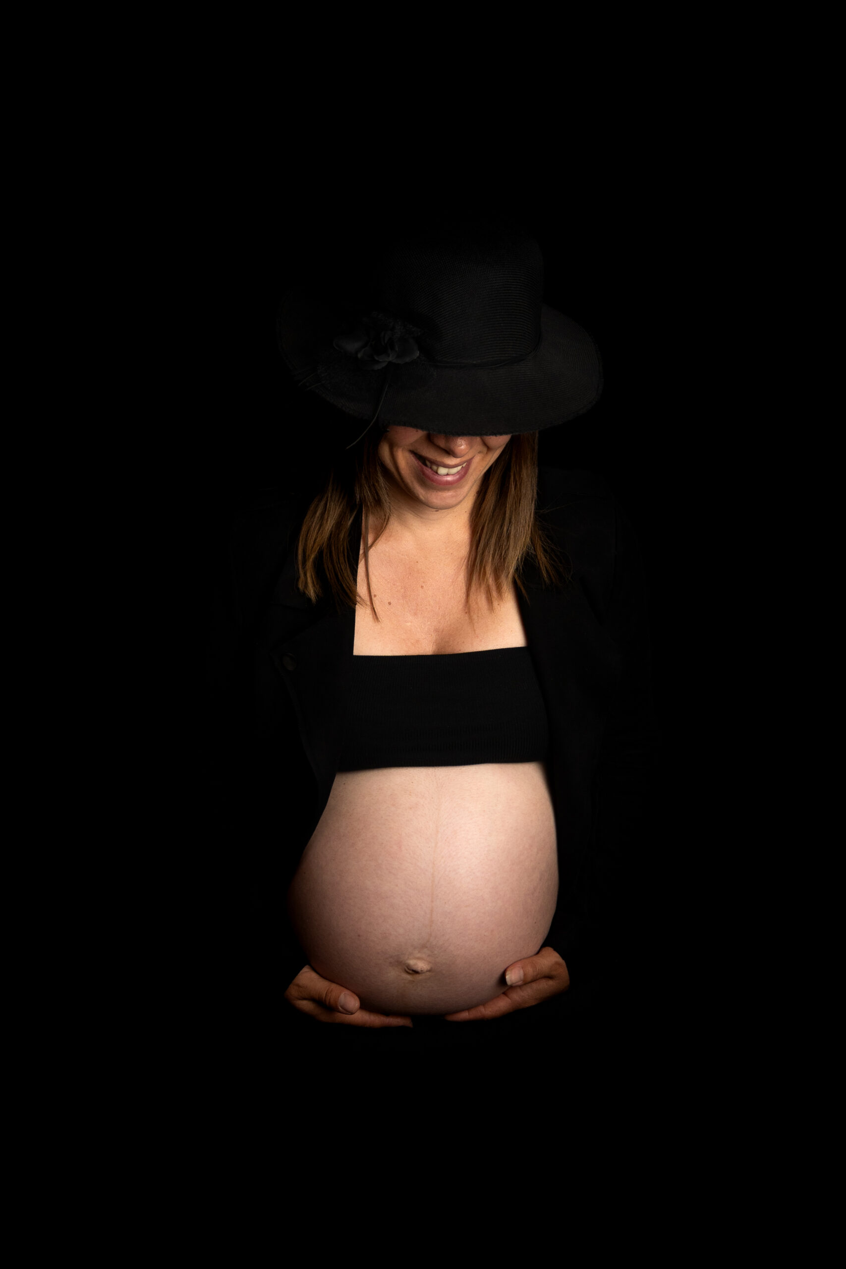 Séance photo grossesse artistique en studio avec éclairage doux et fond noir réalisée par Les 3 P’tits Klics à Odomez près de Valenciennes.